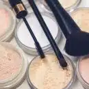 three makeup brushes on top of compact powders