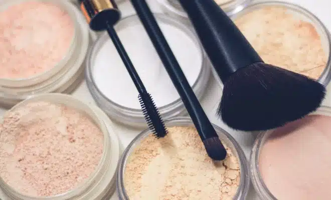 three makeup brushes on top of compact powders