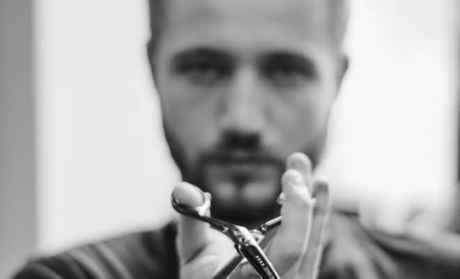 shallow focus photo of man holding scissors
