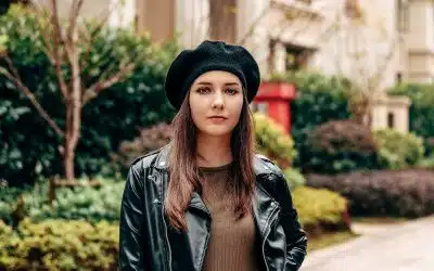 woman in black leather jacket and brown hat standing near green plants during daytime